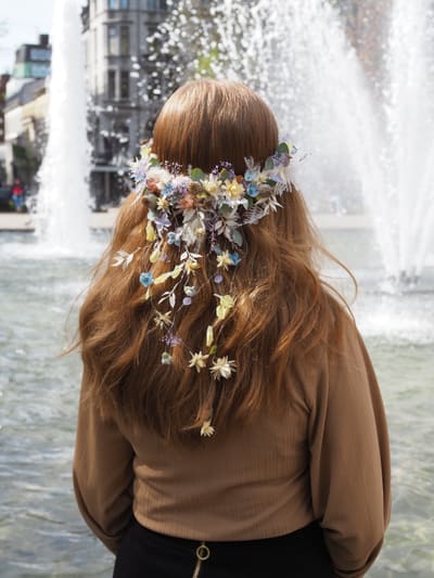 Brud sett bakfra med blomsterkrans i håret foran en fontene