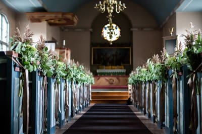 Kirkegang pyntet med blomsterdekorasjoner på benkeradene