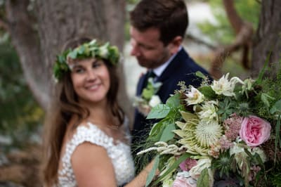 Brud med blomsterkrans i håret og bukett sammen med brudgommen
