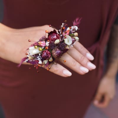 Håndleddskorsasje med små blomster i rosa og vinrødt